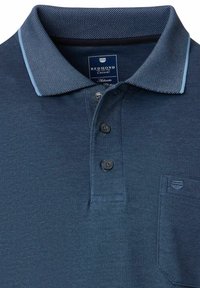 Marineblauw polo shirt met een gestructureerde kraag, drie bruine knopen en een klein borstzakje. De stof heeft een subtiel patroon en een zachte textuur.
