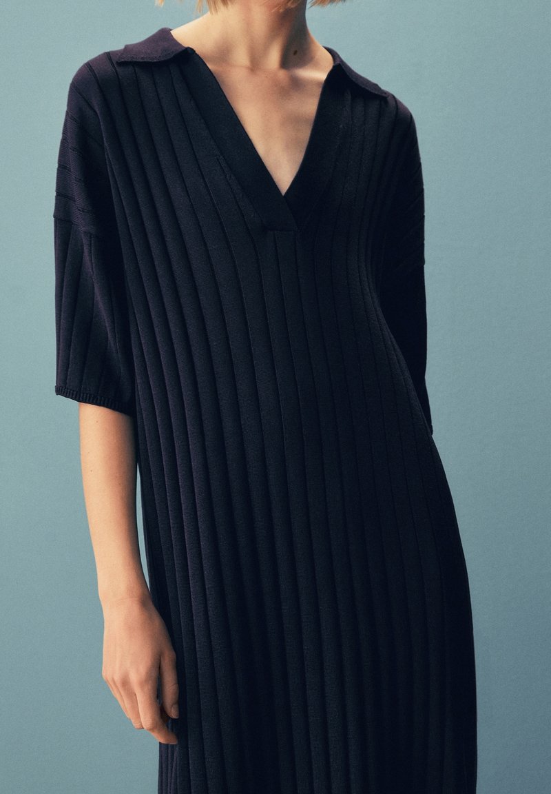 Navy ribbed dress with a V-neck, short sleeves, and a relaxed fit, showcasing vertical stripes and a soft fabric texture.