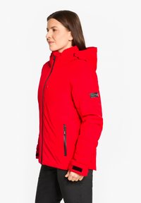 Red insulated jacket with a zip front, adjustable hood, and black accents. Features zippered pockets and Velcro cuffs for a snug fit.