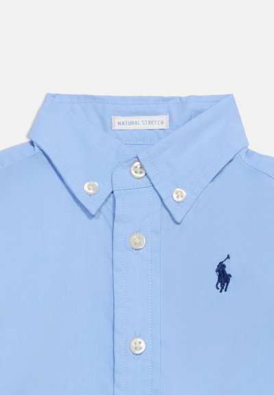 Φωτεινό γαλάζιο πουκάμισο με κουμπιά και λευκά κουμπιά, με σκούρο μπλε κεντητό λογότυπο παίκτη πόλο στο στήθος.