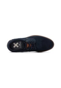 Zapato de ante azul marino con punta redonda, acentos de cuero marrón, cierre con cordones y suela texturizada. Incluye logotipo en la plantilla.