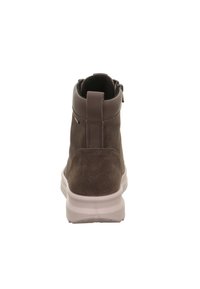 Stivale alla caviglia in suede marrone con un colletto in pelle liscia, bordo superiore imbottito e suola in gomma bianca. Presenta un manico per una facile indossatura.