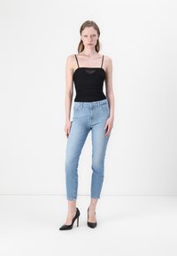 Musthave musta sobiv t-särk õhukeste nööridega, koos helesiniste kitsaste teksade ja mustade kõrgete kontsadega kingadega. Lihtne disain, minimaalne detailitunne.