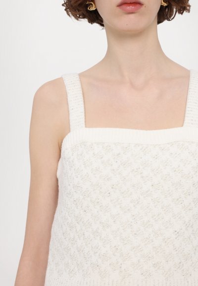 White knit tank top with a square neckline, thick straps, and textured pattern featuring subtle shiny accents. Soft material and breathable.