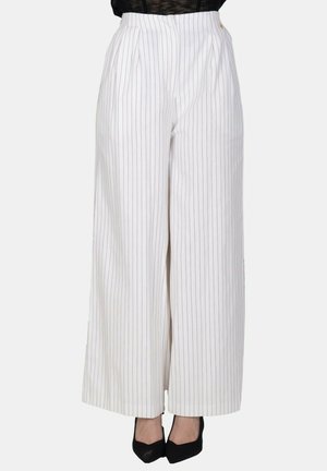 Pantaloni bianchi a vita alta e gamba larga con sottili righe verticali nere, indossati con tacchi neri a punta e top nero.