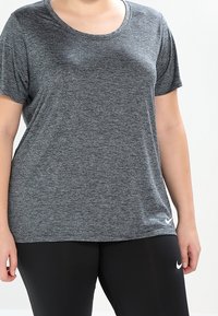 Camiseta atlética de manga corta gris, confeccionada en una tela texturizada, con cuello redondo y un pequeño logo blanco de Nike en la parte inferior delantera.
