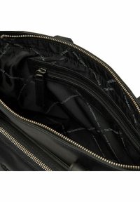 Interior de un bolso de cuero negro que muestra bolsillos con cremallera, tela suave con un patrón de logotipo de la marca y acentos de cremallera de metal.