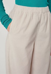Beige geribde corduroy broek met een elastische tailleband en zijzakken, met een gestructureerd oppervlak en een ontspannen pasvorm.