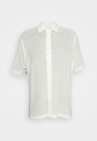 Camisa blanca de botones de manga corta hecha de una tela texturizada con un patrón de malla, que presenta un cuello y un dobladillo recto.