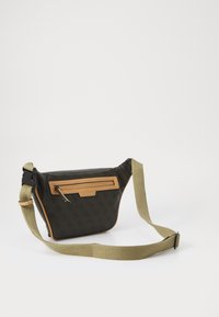 Sac bandoulière en tissu noir avec accents en cuir beige, doté d'une poche avant zippée et d'une sangle ajustable en olive.