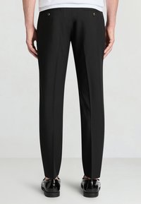 Pantaloni neri eleganti con una vestibilità su misura, dotati di due tasche posteriori con bottoni in ottone, tessuto liscio e design a gamba dritta.