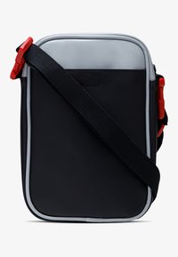 Borsa a tracolla nera con parte superiore argentata, hardware rosso, forma rettangolare e superficie strutturata. Dotata di una tracolla regolabile.