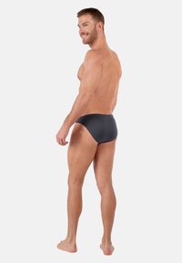 Zwarte zwembaden met een gladde, matte textuur, met een mid-rise ontwerp dat minimale bedekking biedt en een aansluitende silhouet.