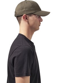 Oliven grøn baseballkappe, lavet af bomuldsstof, struktureret krone, buet skygge, justerbar rem bagpå, modelleret af en person i en sort T-shirt.