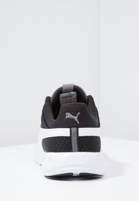 Chaussure de sport noire avec tige en mesh, semelle intermédiaire blanche et accents gris. Présente le logo Puma à l'arrière et à l'arrière, avec des détails texturés sur toute la surface.