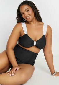 Svart tvådelad bikini med en samlad bralette och högmidjade underdelar, prydd med vita remmar. Slät, stretchig tyg.