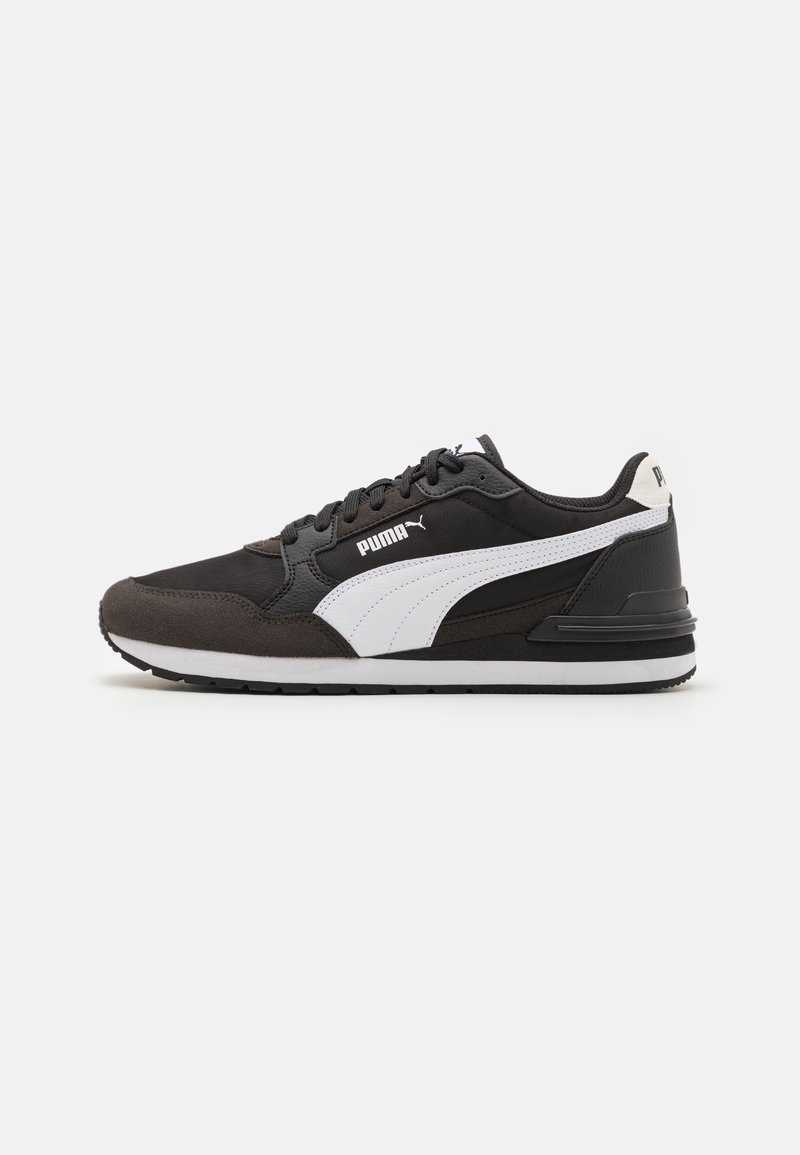 Zapatilla deportiva en blanco y negro con parte superior de ante y malla, que cuenta con un collar acolchado, un logo blanco y una suela de goma con un patrón de tracción distintivo.