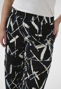 Black pants featuring an abstract white and blue pattern, elastic waistband, and a textured fabric for comfortable fit.