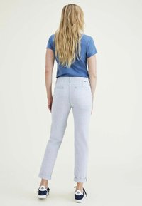 Lichtblauwe gestreepte broek met een opgerolde zoom, gecombineerd met een blauwe t-shirt en witte sneakers. Beschikt over twee achterzakken.