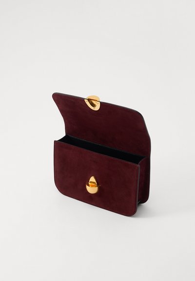 Burgundi nahkahihnainen clutch-laukku, jossa on pyöreä kultaklipsu, avoin muotoilu, joka paljastaa mustan sisäosan, pehmeä rakenne ja sileät reunat.