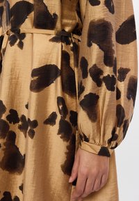 Καφέ σατέν φόρεμα με λεοπάρ σχέδιο σε σκούρο καφέ. Μακριά, φουσκωτά μανίκια με ελαστικούς μανσέτες και αντίστοιχο ζωνάκι στη μέση.