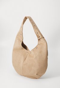 Beige semsket hobo-veske med en avrundet form, som har et topphåndtak og sølvnitter langs åpningen for ekstra detaljer.