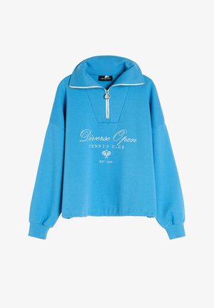 Niebieski sweatshirt z kołnierzem na pół-zamek, z białym logo "Diverse Open TENNIS CLUB" i długimi, lekko bufiastymi rękawami.
