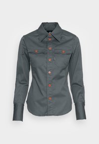 Gray long-sleeve shirt with a pointed collar, two chest pockets, orange buttons, and a curved hemline, made from a smooth fabric.