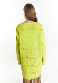 Limegrön stickad lång kofta med geometriska mönster, öppen väv och avslappnad passform som sträcker sig under höfterna.