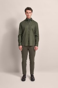 Dark green flannel shirt with a button-down collar, chest pocket, and long sleeves, paired with olive green trousers and brown shoes.