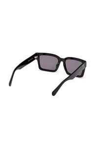 Gafas de sol rectangulares negras con lentes oscuros en degradado, montura de plástico brillante y patillas finas y elegantes con acentos dorados en las bisagras.