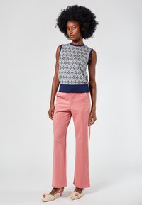 Sleeveless patterned top in light blue and white, paired with pink trousers. Footwear features a cream texture with pink accents.