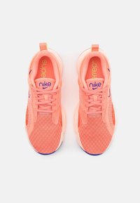 Růžové síťované tenisky s texturovaným povrchem, doplněné fialovými a zelenými akcenty, zakřivenými podrážkami a kontrastní patní paticí.