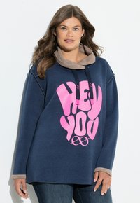 Granatowa, oversize'owa bluza z beżowym kołnierzem, z dużym różowym napisem "HEY YOU" i miękką fakturą. Długie rękawy.