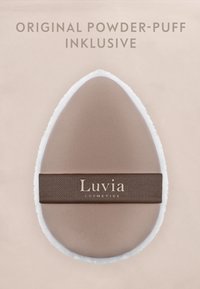 Éponge à poudre de maquillage beige en forme de goutte d'eau avec des bords blancs et une sangle marron portant la marque "Luvia Cosmetics" sur un fond clair.