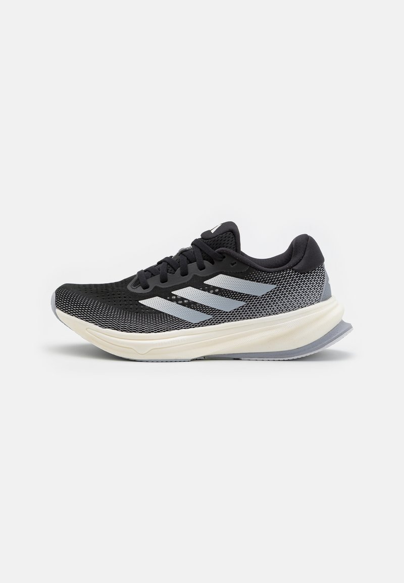 Baskets de sport noires et grises avec une tige en mesh, trois bandes argentées, semelle rembourrée et talon arrondi pour la stabilité et le soutien.