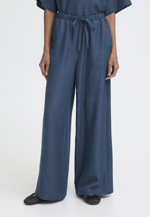 Marineblå vidde bukser med elastisk taljebånd og snøre, båret med sorte flade sko, vist fra taljen til fødderne.