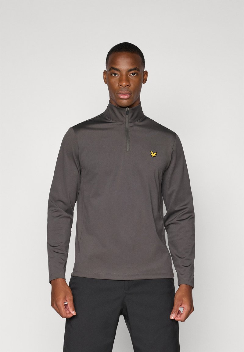 Grå zip-neck pullover lavet af glat stof, med lange ærmer og et lille gult fuglelogo på venstre bryst.