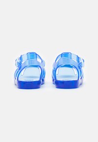 Sandalias transparentes azules con un diseño abierto. Cuentan con correas ajustables, una plantilla texturizada y una suela resistente para mayor comodidad.