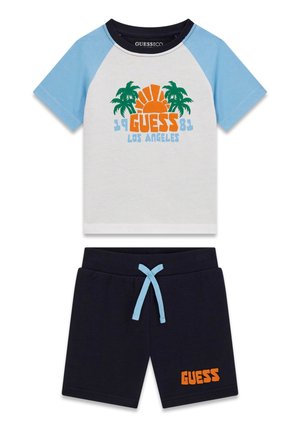 Ensemble pour enfants à manches courtes composé d'un haut bleu et blanc avec un motif de palmier et de soleil, et un short marine avec un cordon bleu et le texte "GUESS" en orange.