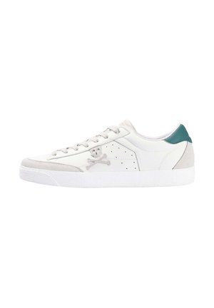 Zapatilla de cuero blanca con detalles en gamuza gris, que presenta un talón en color teal; adornada con un logo de calavera y huesos cruzados y detalles perforados.