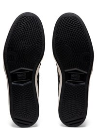 Czarne gumowe podeszwy trampek z teksturowanymi wzorami chwytowymi; białe akcenty boczne; heksagonalny detal logo na środku.