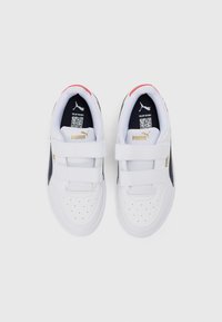 Witte sneakers met een gladde leren afwerking, klittenbandsluitingen, marineblauwe accenten, geperforeerde neus en rode hielloop met gouden logo-elementen.