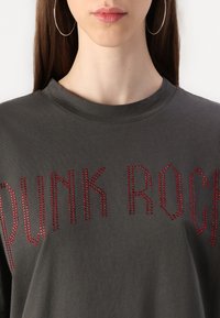 Szara bawełniana koszulka z czerwonymi literami z kryształków, na których napisano "PUNK ROCK", z okrągłym dekoltem i luźnym krojem.