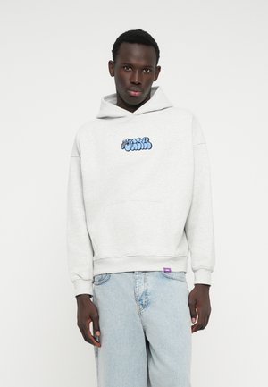 Sweatshirt cinza com capuz e logo gráfico azul no peito, bolso frontal e punhos canelados. Usado com jeans de denim azul claro.