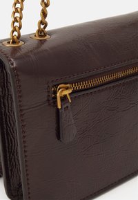 Borsa in pelle marrone con una finitura testurizzata, dotata di una tracolla in metallo tono oro e di un comparto con zip con un cursore abbinato.
