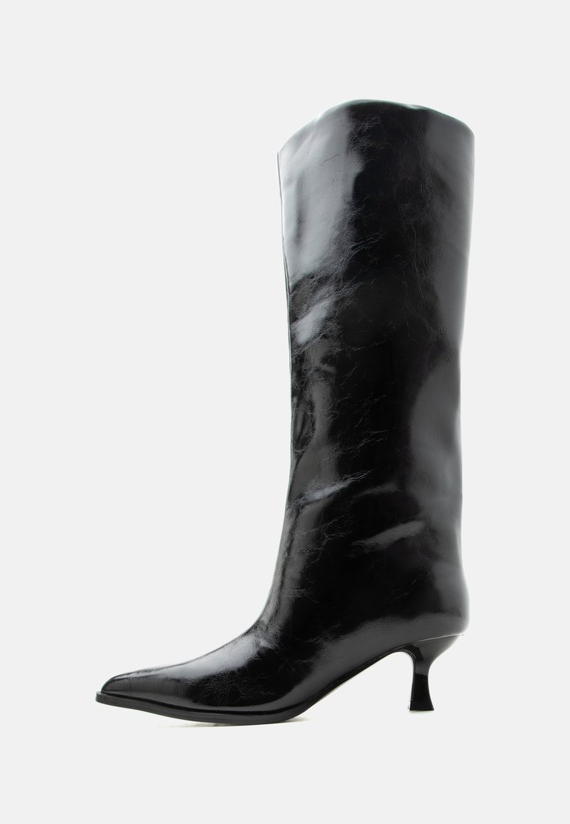 Μαύρη γυαλιστερή δερμάτινη μπότες μέχρι το γόνατο με μυτερό δάκτυλο και χαμηλό κυρτό τακούνι σε απλό φωτεινό φόντο.