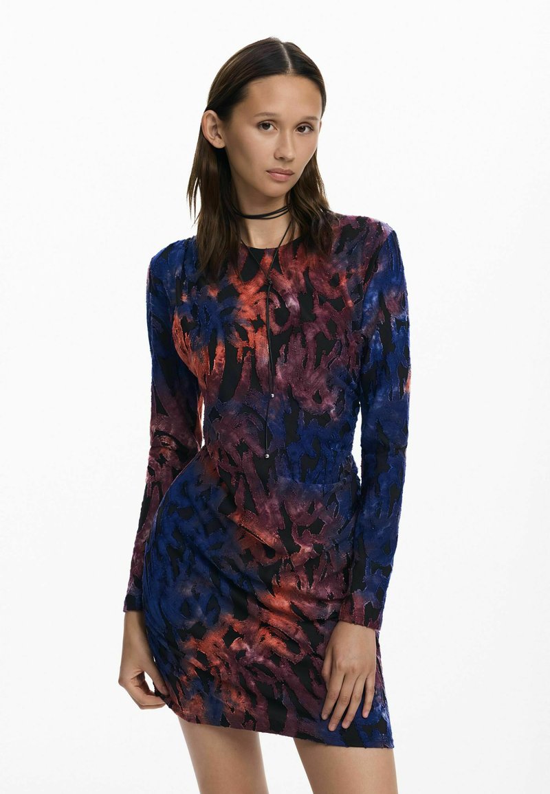 Hosszú ujjú miniruha sötétkék, lila és piros absztrakt mintákkal; testes, testhezálló sziluettel és puha, texturált anyagból készült.