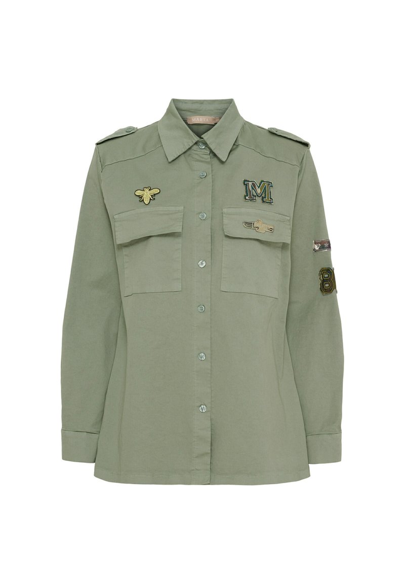 Grön långärmad skjorta med knäppning, dubbla bröstfickor och broderade lappar inklusive en bi och bokstaven "M".
