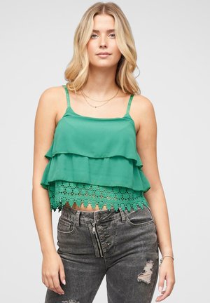 Zeleni, slojeviti crop top s čipkastim rubom. Izrađen od lagane tkanine, sa tankim podesivim trakama. Nosite s tamnim, istrošenim trapericama.